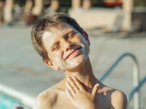 A teenage boy applies sunscreen.