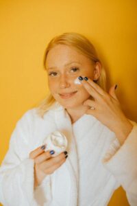 A girl is applying cream to her face.