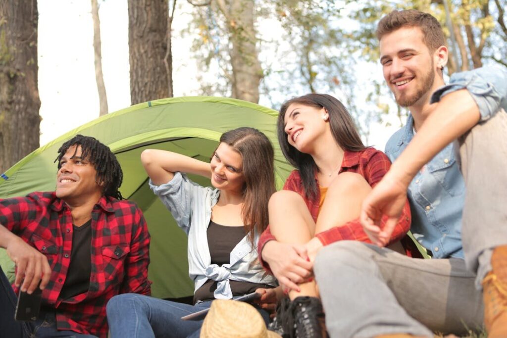 Two Men and Two Women with No Visible Sun Protection Sit Outside a Tent in the Woods