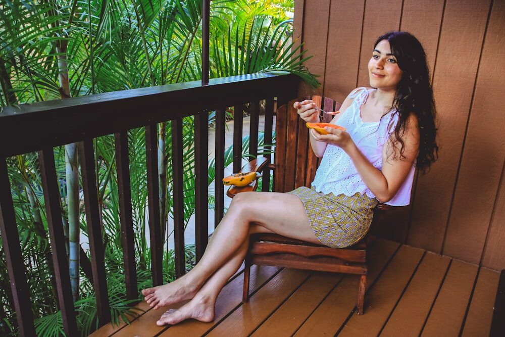 A Woman Sits at a Porch Eating Papaya for an Even Skin Tone