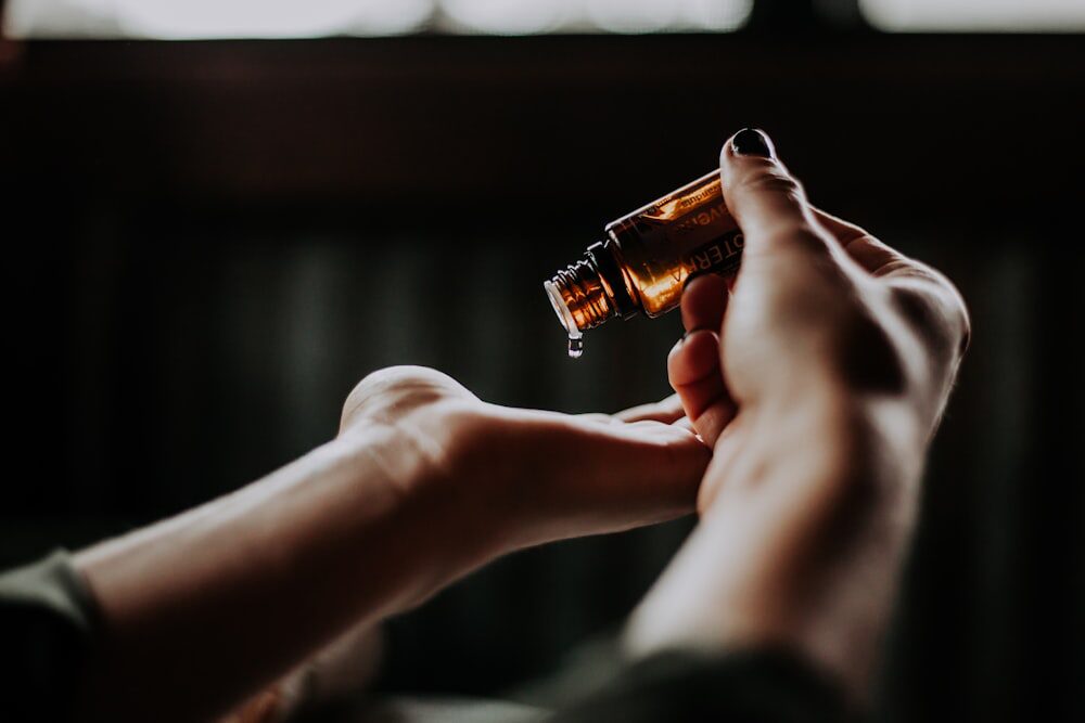 A person pouring liquid from an amber glass bottle 