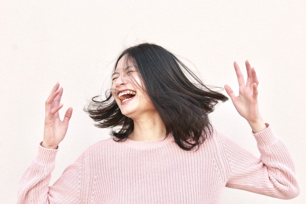 A with Healthy Hair Flips it Around as She Laughs at Something