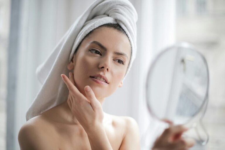 A woman touching her face as she looks into the mirror