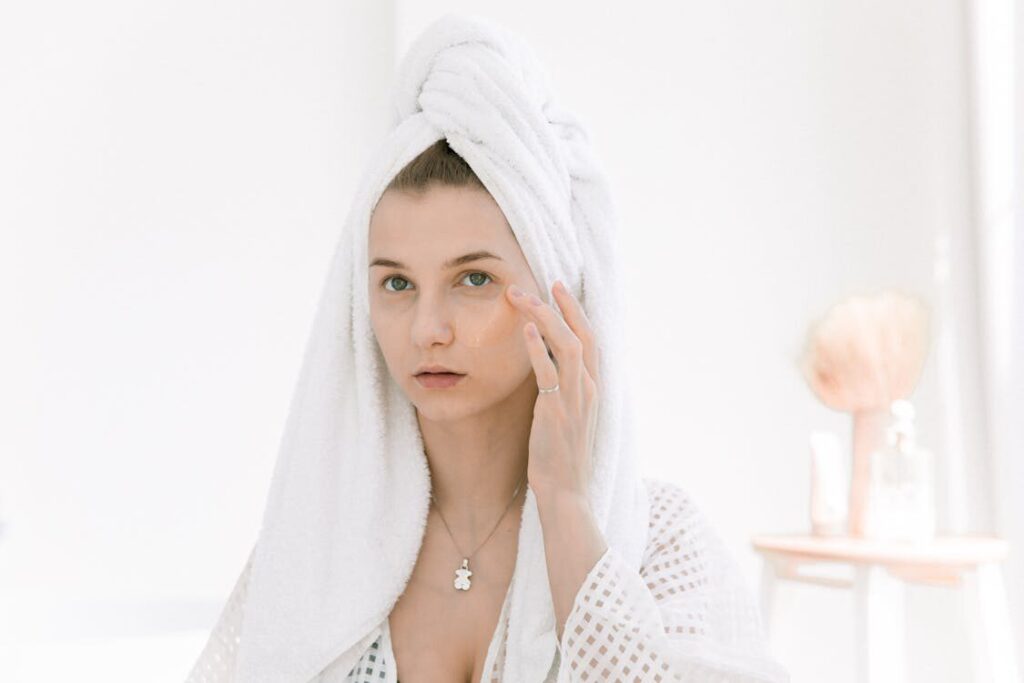 A woman wearing a towel while touching her face