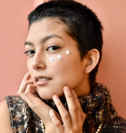 A woman applying cream on her face